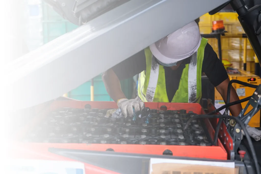 A technician cleaning the battery on a forklift